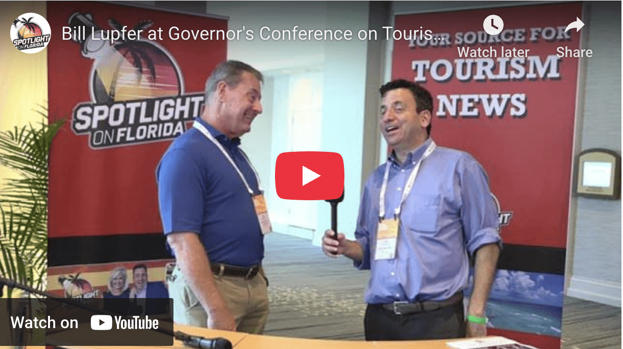 Two men talking at tourism conference booth.